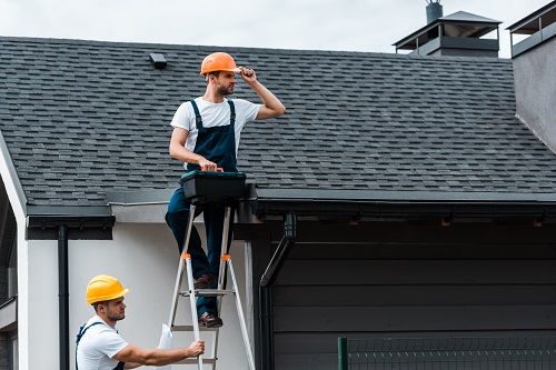 repairman sitting on roof and holding toolbo